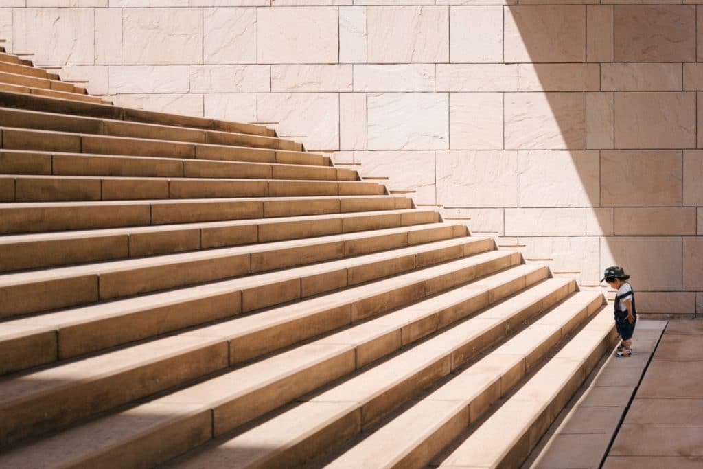 toddler standing at base of wide marble staircase