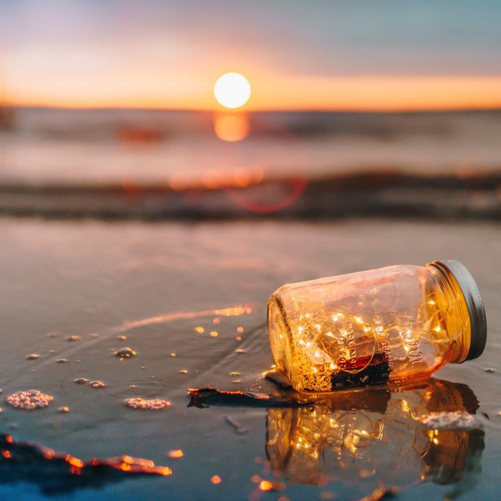 fairy lights in a glass bottle on a sunset beach