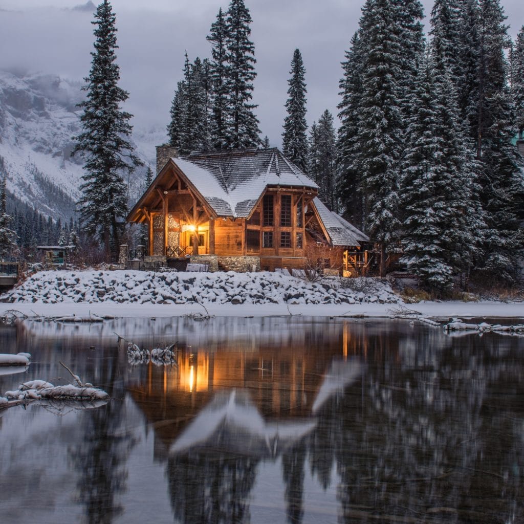 winter wooden cabin light within on a snow lakeshore