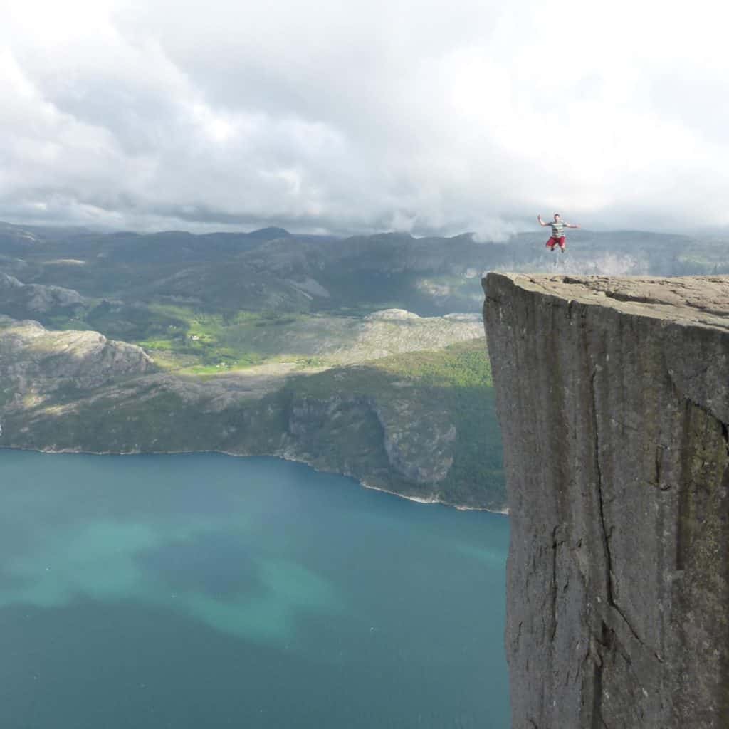 man leaping with joy on cliff edge