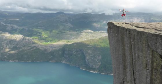 man leaping with joy on cliff edge