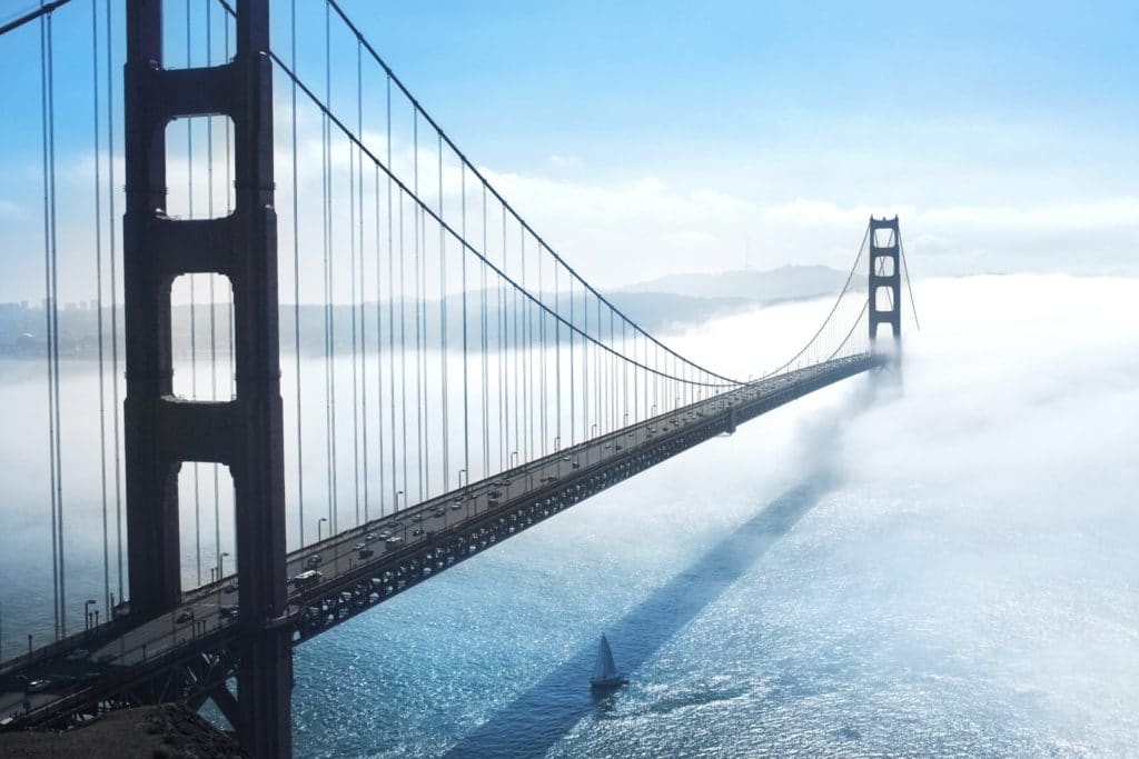 large suspension bridge over water into fog