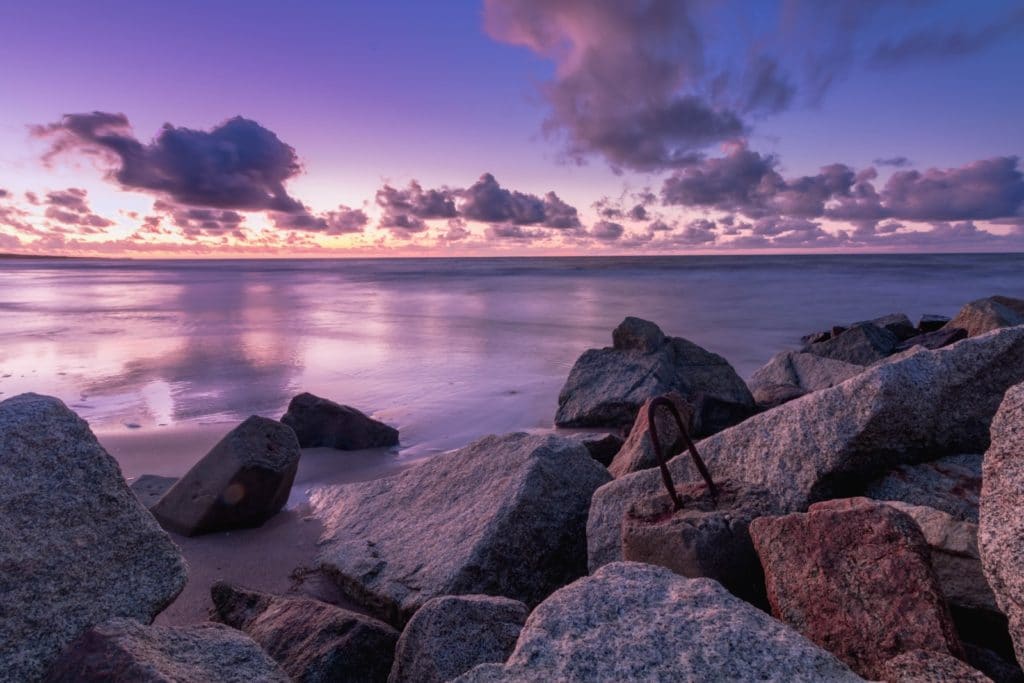 sunset over boulders and water lavender sky