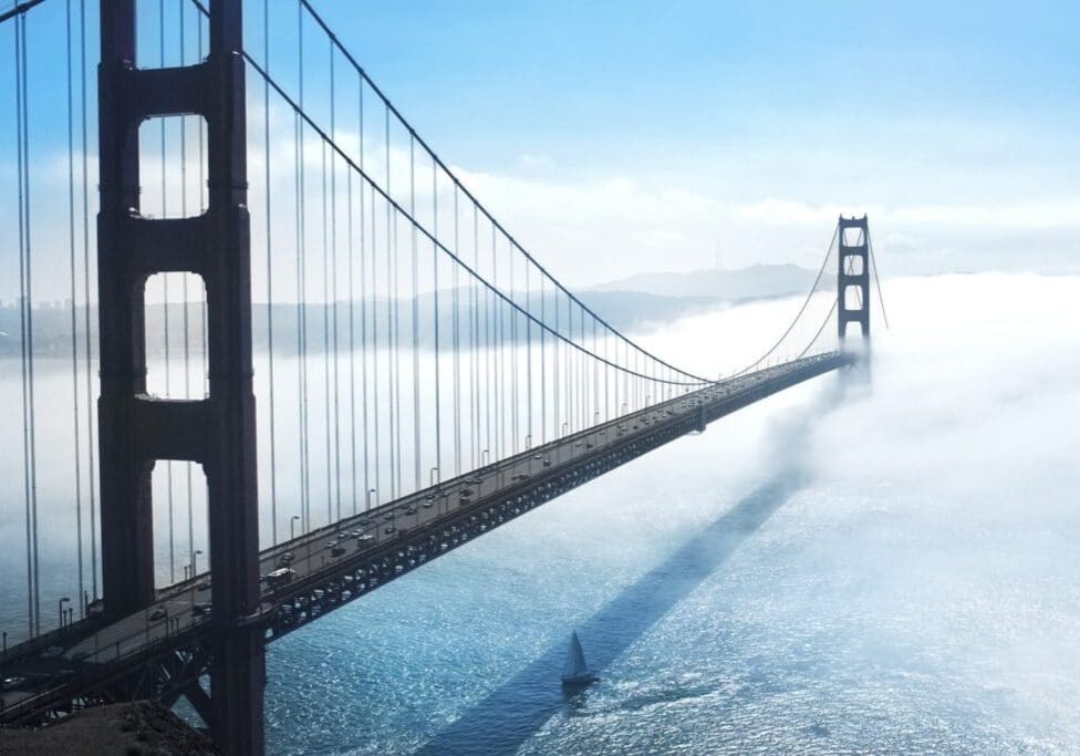 large suspension bridge over water into fog
